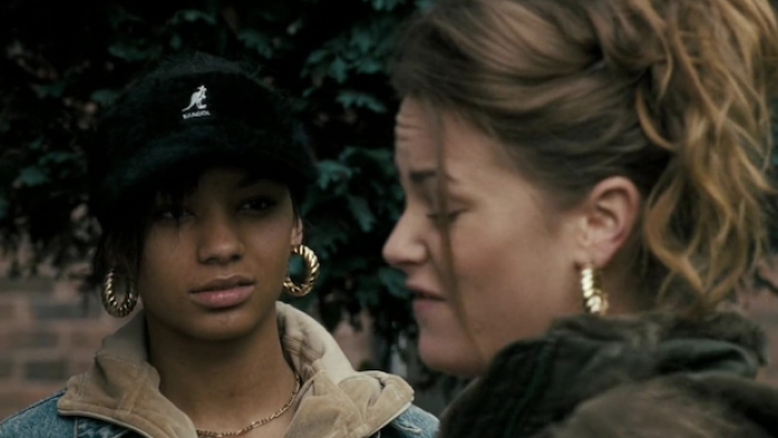 Kidulthood: Two teenage girls conversing outdoors, one wearing a cap and the other with her hair tied up
