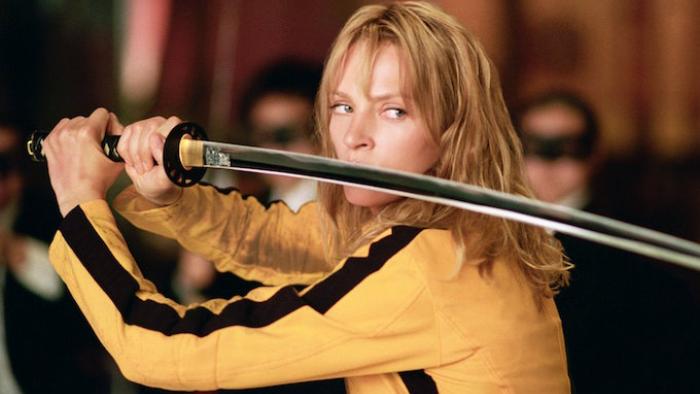 Kill Bill: Vol. 1 movie: Uma Thurman in a Bruce Lee-inspired yellow jumpsuit holds up a katana in a ready pose