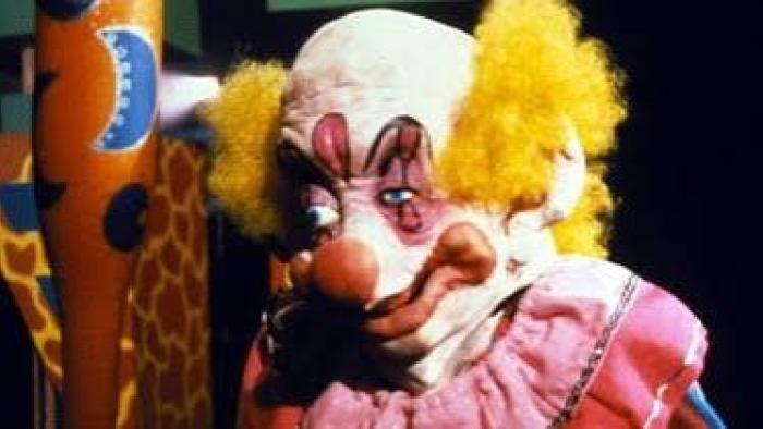 Killer Klowns from Outer Space: Creepy clown with yellow hair and a pink outfit against a dark backdrop.