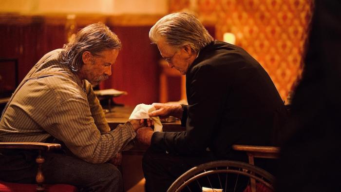 Killing Faith Movie: Bender sits opposite Preacher Ross, as the latter bandages the former's wounded hand