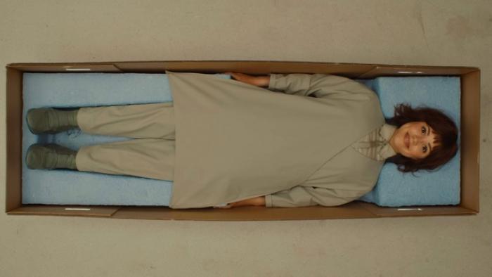 Klara and the Sun Movie: Klara lies on her back in a cardboard box, smiling