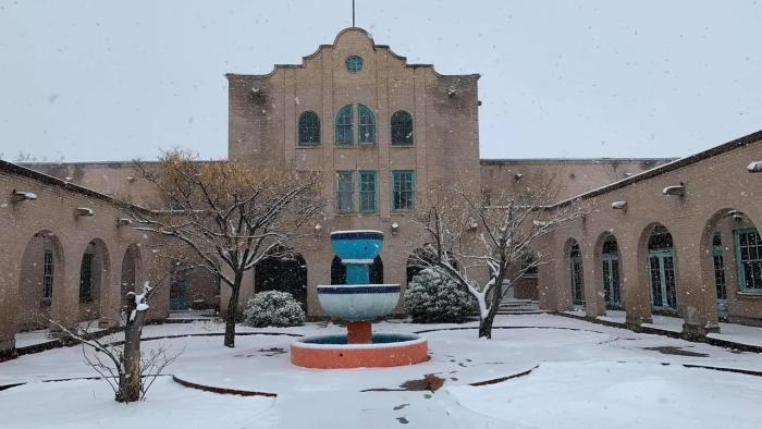 Letters at Christmas: The courtyard entrance to an historic Southwest-style building with a fountain, bare trees, and covered in a layer of snow.