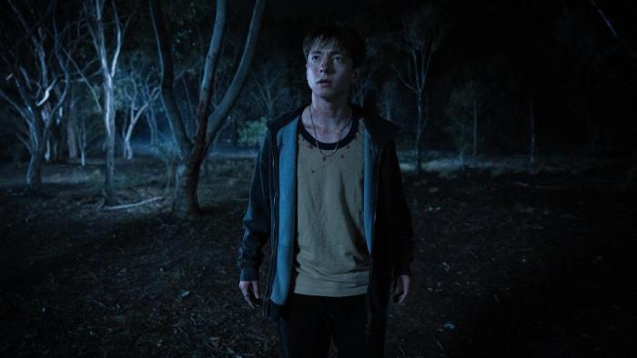 Leviticus Movie: Looking injured and worn-out, Naim (Joe Bird) regards something warily in the dark woods