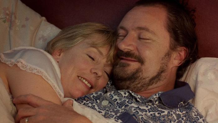 Life Is Sweet: A husband and wife both smile as they cuddle up in bed