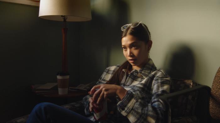 Lousy Carter Movie: Gail (Luxy Banner) sits in a chair in Carter's office, glasses perched on her head, beer can in hand