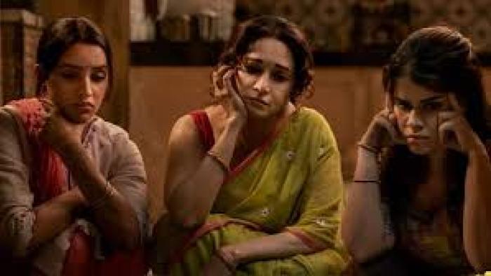 Maa Behen: Three Indian women sit closely, appearing thoughtful and pensive, in a warmly lit room.