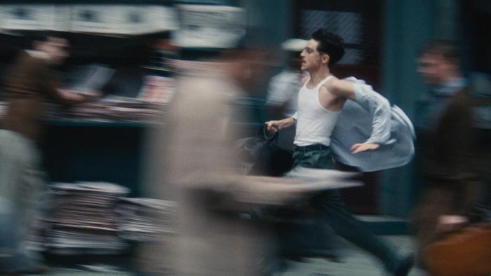 Marty Supreme movie: Marty runs down a busy sidewalk