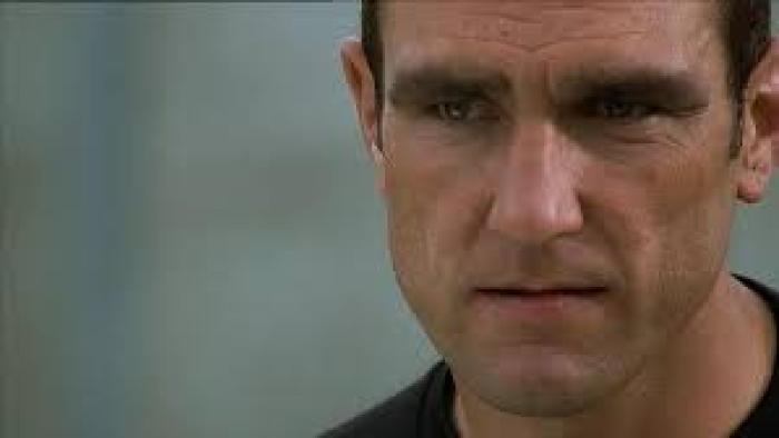 Mean Machine: Close-up of a stern-looking man with short dark hair wearing a black top, with an intense or troubled expression on his face
