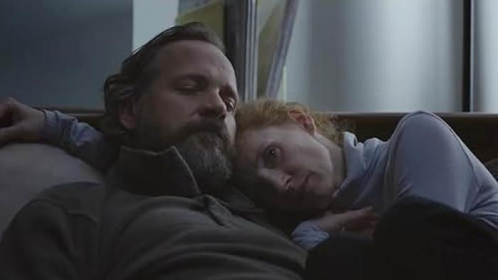Memory Movie: Saul and Sylvia (Jessica Chastain) cuddle on a couch, Sylvia resting her head on Saul's shoulder