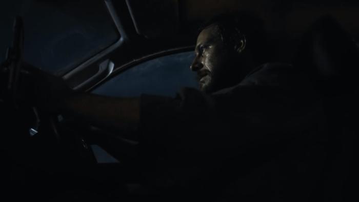 Mercy Road: A side view of a dishevelled, bearded White many driving in a car.