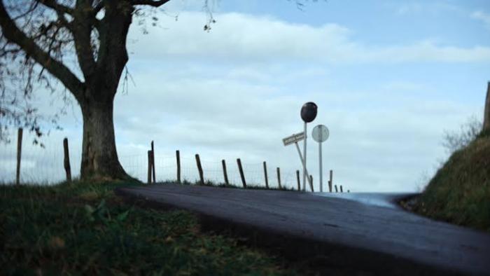 Miguel Ángel Blanco: The 48 Hours that Changed Spain Movie: Rural road with a tree, fence, and traffic signs under a cloudy sky.
