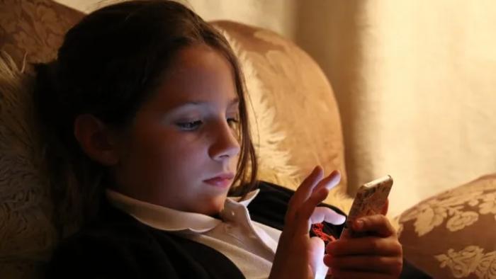 Molly vs the Machines: Ivy Blackshaw plays Molly in a reconstruction as she sits in a dimly-lit room scrolling on her phone