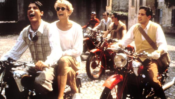 A Month by the Lake: Vanessa Redgrave smiles joyously, sitting behind a young man on the back of his motorbike, other motorbikes riding alongside