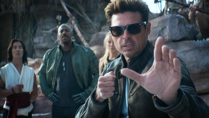 Mortal Kombat II Movie: In dark glasses, Johnny Cage raises his hands, readying for battle, with his fellow champions behind him