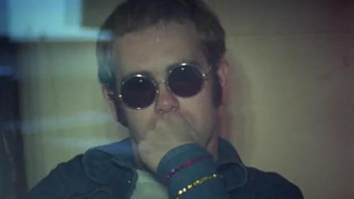 Elton John -- Never Too Late: A younger Elton John wearing sunglasses with his hand to his mouth