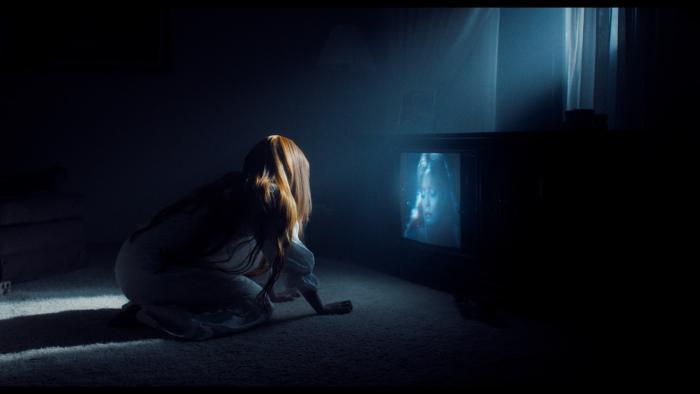 My Animal Movie: A teen with red hair and pale skin wearing a white nightgown crawls toward a TV showing a woman's image at night