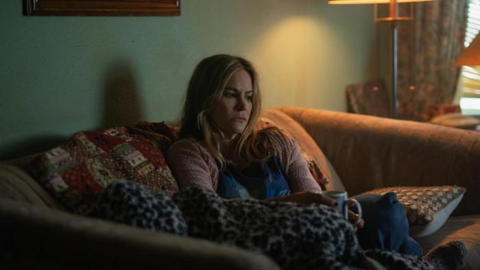 Night Always Comes: A middle-aged woman sits on a sofa looking concerned