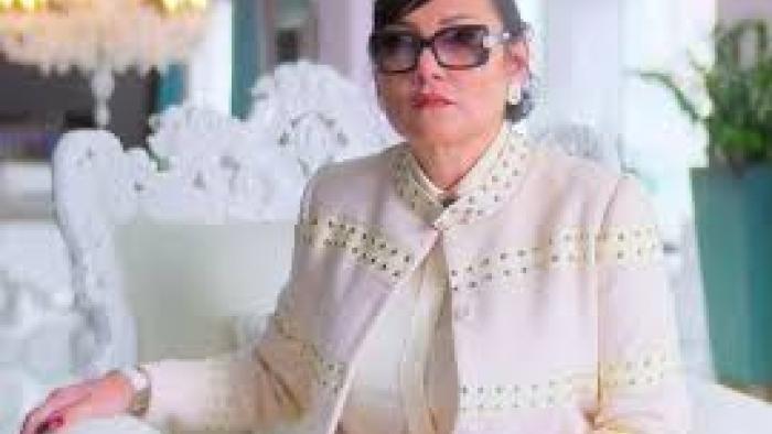 Nelma Kodama: Woman in white wears sunglasses indoors