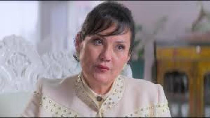 Nelma Kodama: Woman in white suit looks at camera