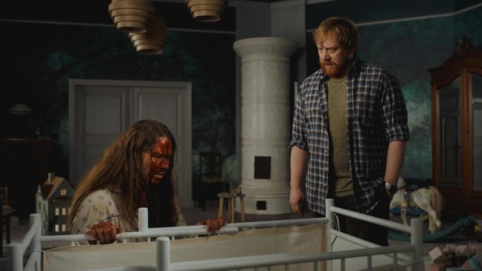 Nightborn: Woman with blood on face kneeling by a crib, man standing beside her, both look distressed