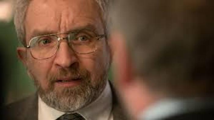No Ordinary Heist: Elderly man with glasses and beard in a suit, looking serious