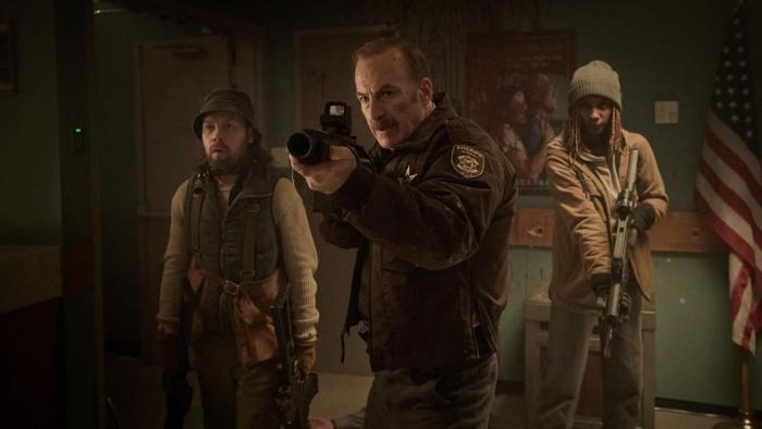 Normal Movie: Ulysses, flanked by bank robbers Keith and Lori, points a grenade launcher at his attackers