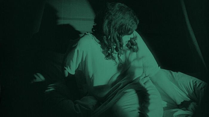 Greta Schröder tosses and turns beneath her bedsheets in the dark in Nosferatu: A Symphony of Horror