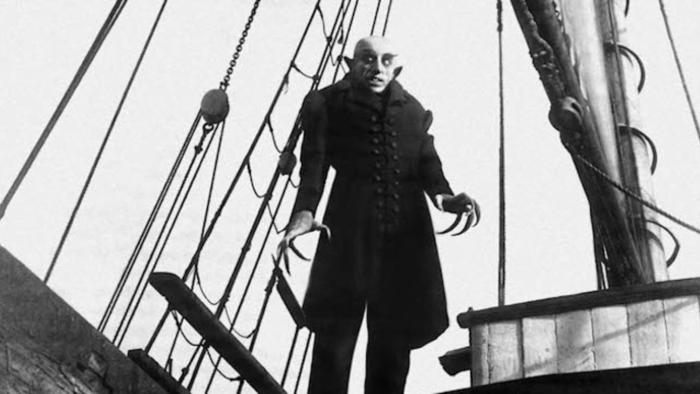Max Schreck towers up from the deck of a boat, his figure in silhouette against the sky in Nosferatu: A Symphony of Horror