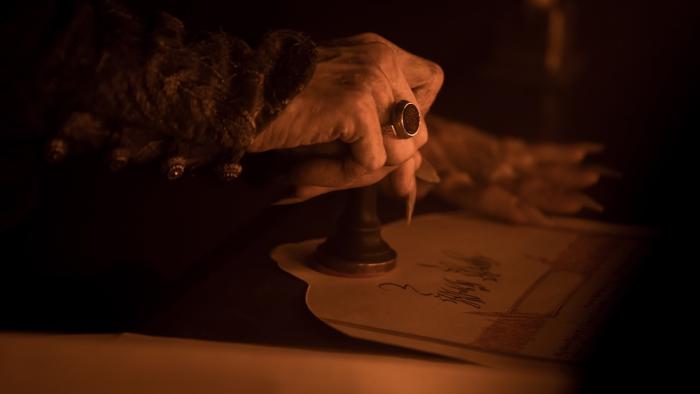 Nosferatu Movie: Menacing hand with long, pointy nails and an ancient ring, stamps a seal on a document