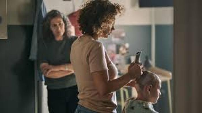 Nothing to Lose movie: Woman shaving another's head in a dimly lit room; an onlooker watches intently.