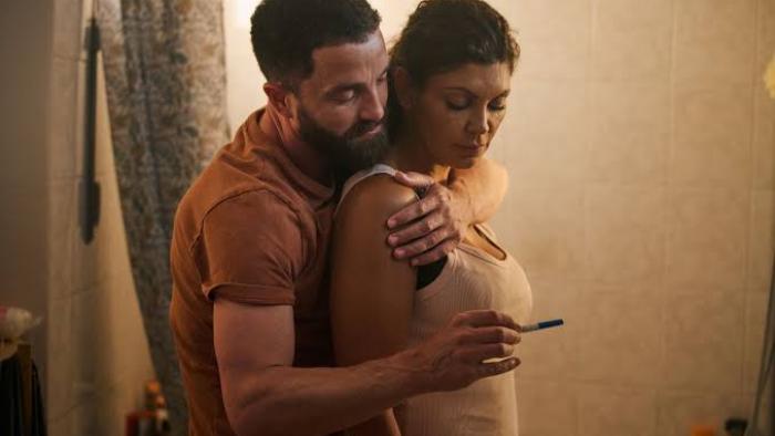 Nothing to Lose movie: Man hugging woman holding pregnancy test in bathroom.