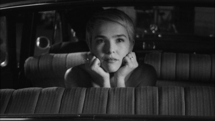 ouvelle Vague Movie: Jean Seberg (Zoey Deutch) rests her chin on her wrists, while looking out the back window of a car