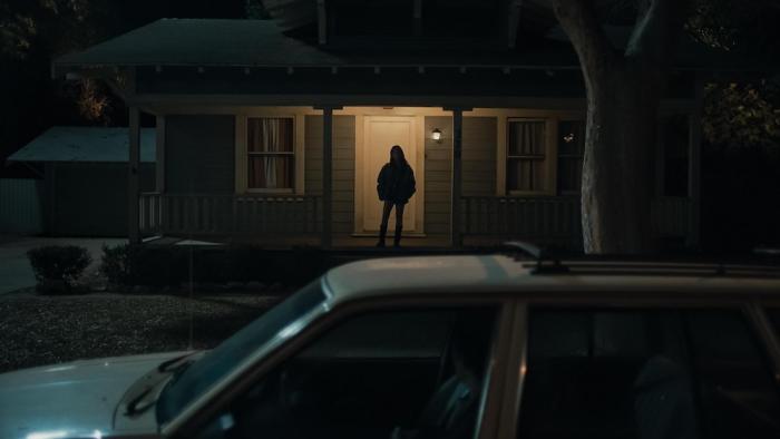 Obsession Movie: On the front porch of a house, a woman's silhouette looks menacing