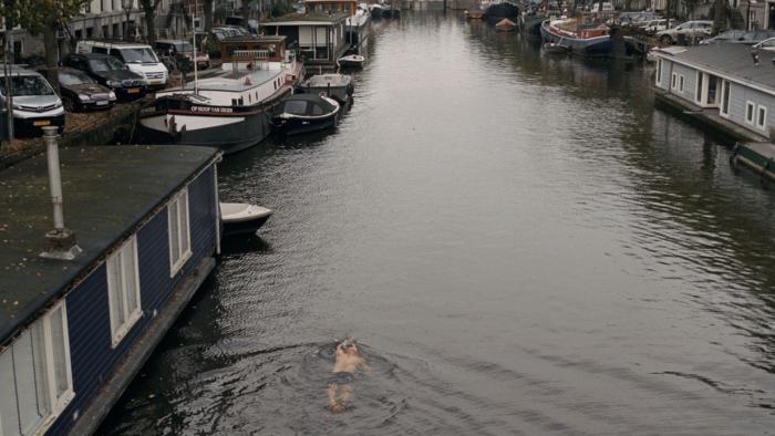 Occupied City Movie: A man swims in an Amsterdam canal