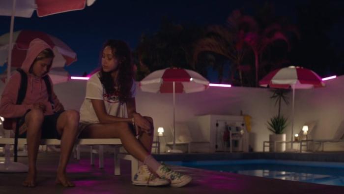 Ocean Boy: A teenage boy and girl sit on sun lounger next to a swimming pool at night