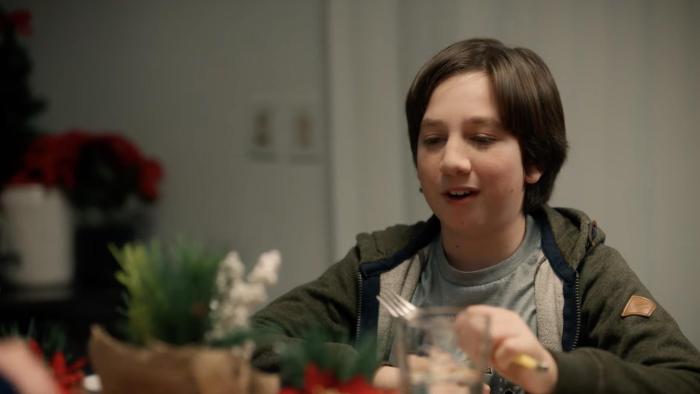 Dog Patrol: Operation Santa Paws movie: A child with dark brown hair smiles at a kitchen table