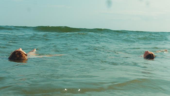 Over/Under: Two girls floating in a calm ocean under a clear sky