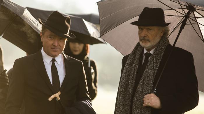 Blackbird: Characters dressed in black suits and ties attend a funeral