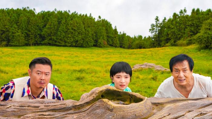 Panda Plan Movie: David (Wei Xiang), Xiaozhu (Shi Ce), and Jackie (Jackie Chan) watch something while crouched behind a log