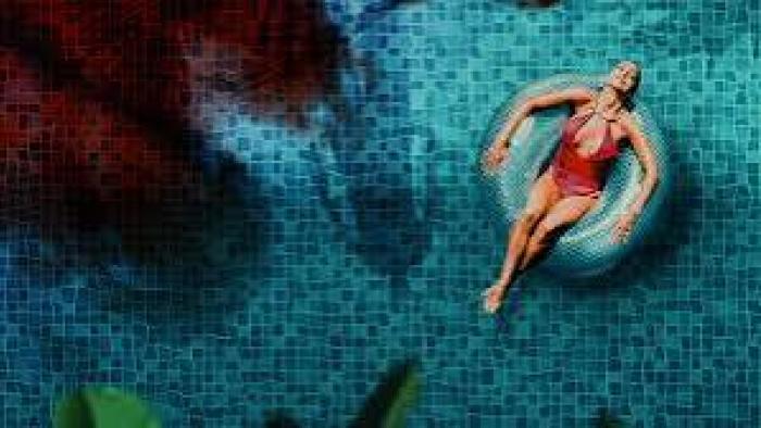 The Paradise Murders: A woman in a red swimsuit floats on a ring in a blue-tiled pool.