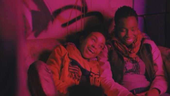 Pariah Movie Poster: Two people on a couch, laughing under pink lighting.