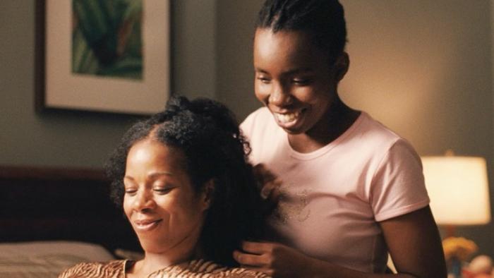 Pariah Movie Poster: Woman styling another woman's hair, both smiling warmly in a softly lit room.