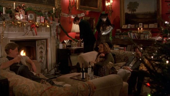 Peter Friends: Two characters sit on sofas, and another fixes a drink behind them, in a living room decorated for Christmas