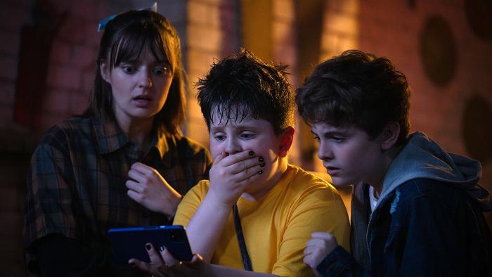 Pinocchio Unstrung Movie: Mia, Dudley, and James react to something shocking they see on a smartphone