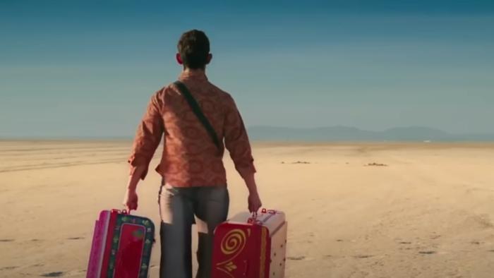 PK: PK the alien walks in a desert holding two suitcases