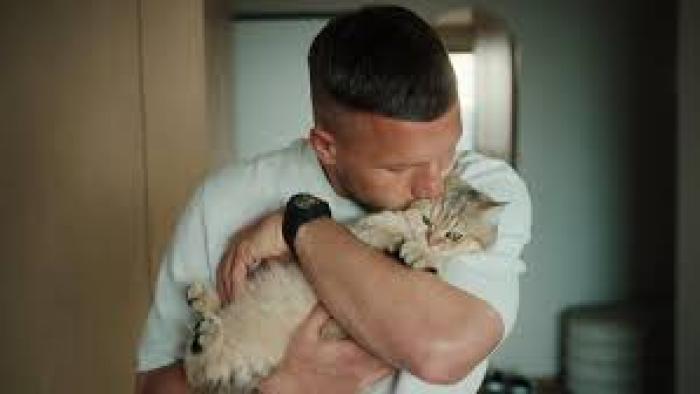 Poldi: Poldi hugging a fluffy cat indoors.