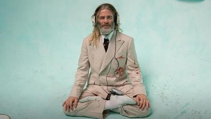 Poolman Movie: Darren meditates in the bottom of an empty pool, wearing a cream-colored suit and headphones