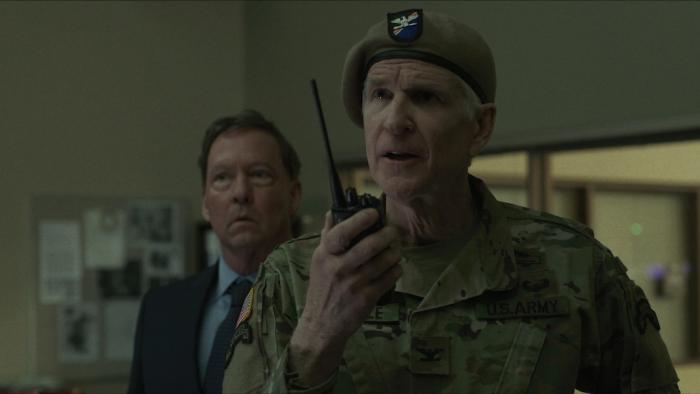 Protector Movie: Colonel Joseph Lavelle speaks into a walkie while police captain Michaels looks on from behind