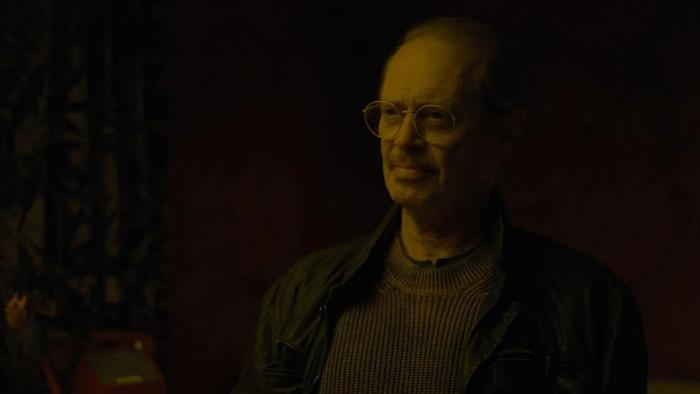 Steve Buscemi sits in the darkness