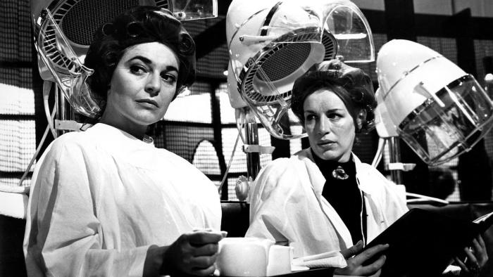 The Pumpkin Eater: Anne Bancroft sits in a chair at a hair salon, a woman looking at her intensely to her left